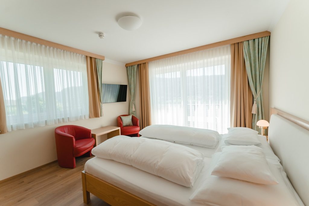 Zimmer mit Doppelbett, Sessel und Fenster zum Garten