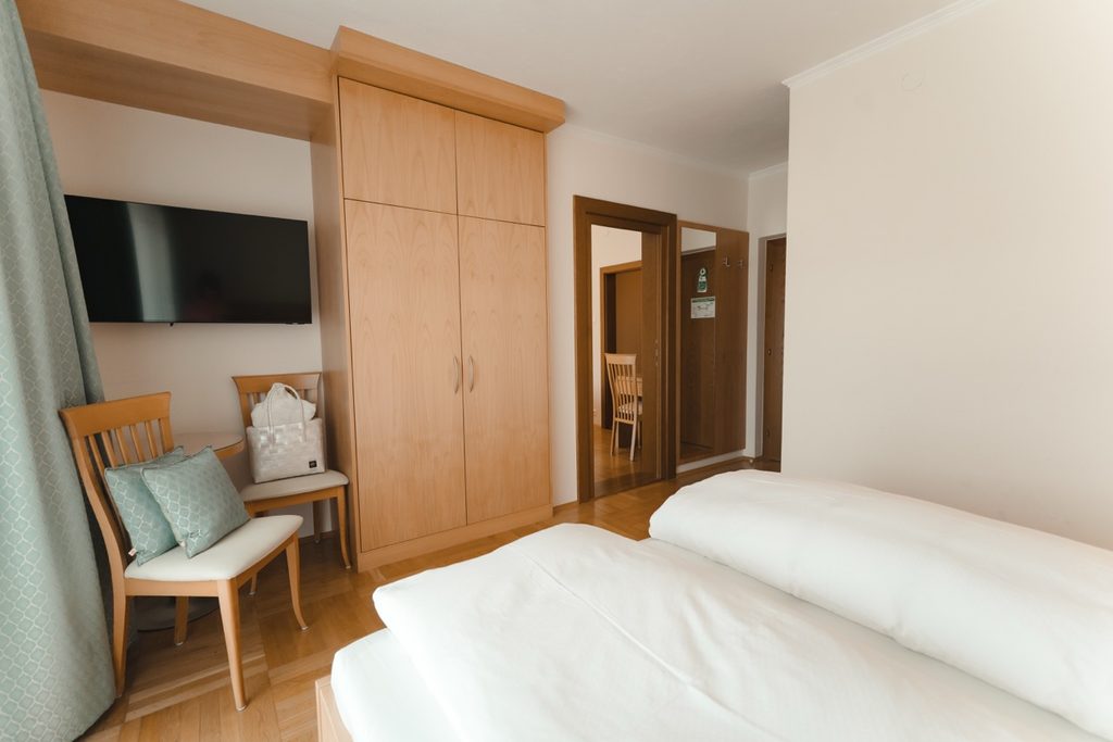 Zimmer mit Doppelbett, Schrank und Sitzplatz am Fenster